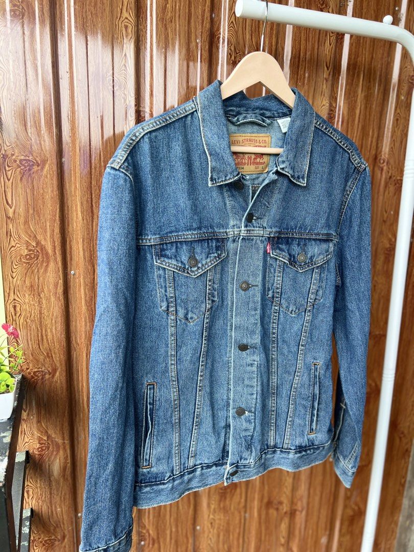 Levi's Trucker Denim Jacket Blue (Category: Coats, Jackets and Outerwear) located in Bago City. Submitted by g___shop (Listing ID 1462346019, Image 3). Description: - Classic Levi's denim jacket - Medium blue wash - Button front closure - Two chest pockets with button flaps - Side pockets - Standard collar - Estimated size: Large - Ideal for layering or standalone wear - Versatile wardrobe staple.