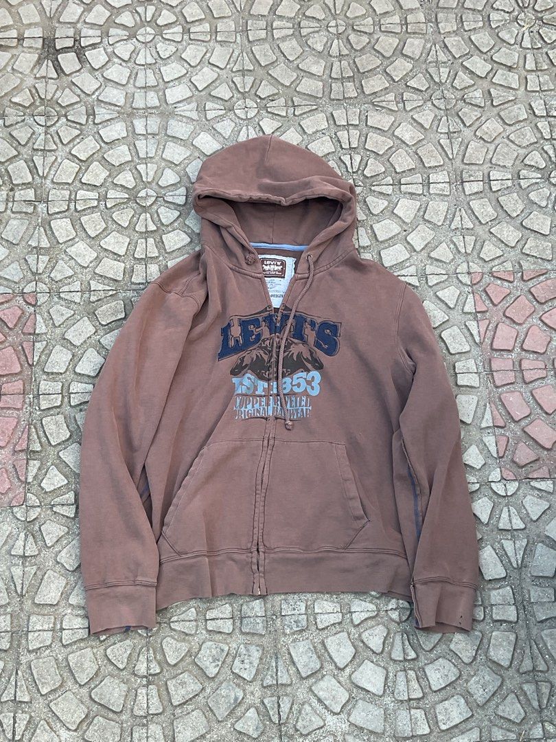 Levi's Zip-Up Hoodie (Category: Hoodies) located in Mabalacat. Submitted by epicforest_78284 (Listing ID 1462398930, Image 1). Description: - Brown Levi's zip-up hoodie - Features a graphic print on the front with 'Levi's' and numbers - Drawstring hood for adjustable comfort - Convenient front pocket - Ideal for everyday casual wear.