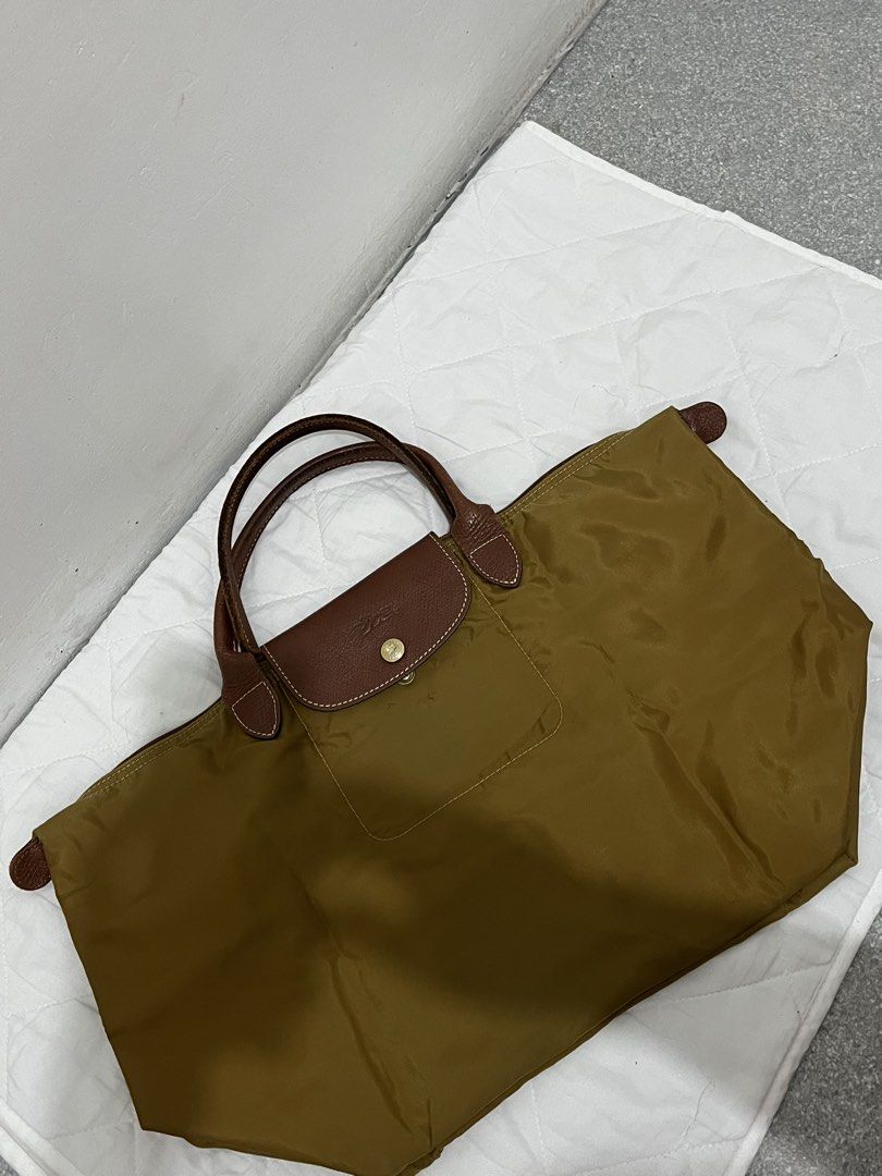 Longchamp Le Pliage Tote Bag (Category: Luxury Bags & Wallets) located in Manila. Submitted by lai.p (Listing ID 1462373511, Image 1). Description: - Classic Longchamp tote bag - Color: Olive green nylon with brown leather handles and trim - Spacious main compartment - Folds flat for easy storage - Ideal for travel or everyday use - Front pocket with snap closure.