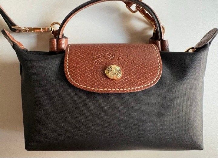 Longchamp Mini Pouch /Crossbody bag (Category: Purses & Pouches) located in Navotas City. Submitted by riyuwi (Listing ID 1462354717, Image 2). Description: PreOwned lightly Used Longchamp Pouch Mini hand/Crossbody bag - Elegant Brown Leather Trim & Handle - Detachable Shoulder Strap for Versatility - Secure Zipper Closure - Stylish Gold Hardware - Ideal for organizing essentials or as a standalone clutch XXS -Micro Sized Sign of Used sa detachab