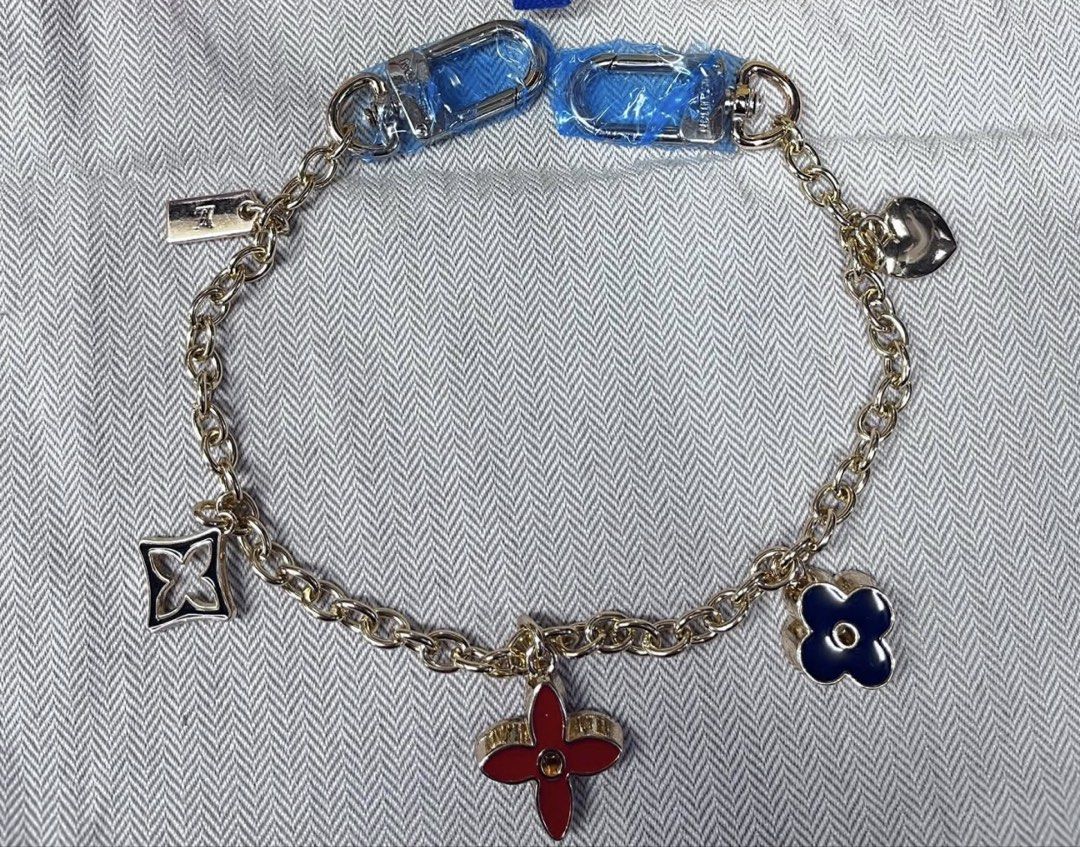 Louis Vuitton Charm Bag Bracelet with Multiple Charms (Category: Webcams) located in Angeles City. Submitted by migs_font29 (Listing ID 1462365362, Image 1). Description: - Gold-tone chain bracelet - Features multiple charms: lock, quatrefoil, heart, and two floral motifs - Floral charms include one red with crystal accent and one navy blue - Two clips attached at the top - Perfect accessory to enhance your jewelry collection.