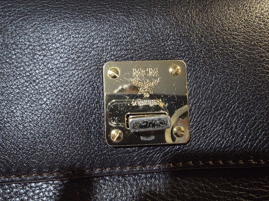 MCM Black Leather Top Handle Bag (Category: Luxury Bags & Wallets) located in Mandaluyong City. Submitted by artlin04 (Listing ID 1462307012, Image 2). Description: - Authentic MCM handbag in classic black leather. - Elegant gold-tone hardware, including the signature MCM logo clasp. - Spacious interior with MCM logo lining and a convenient zippered pocket. - Features sturdy top handles for comfortable carrying. - Secure flap closure to keep your
