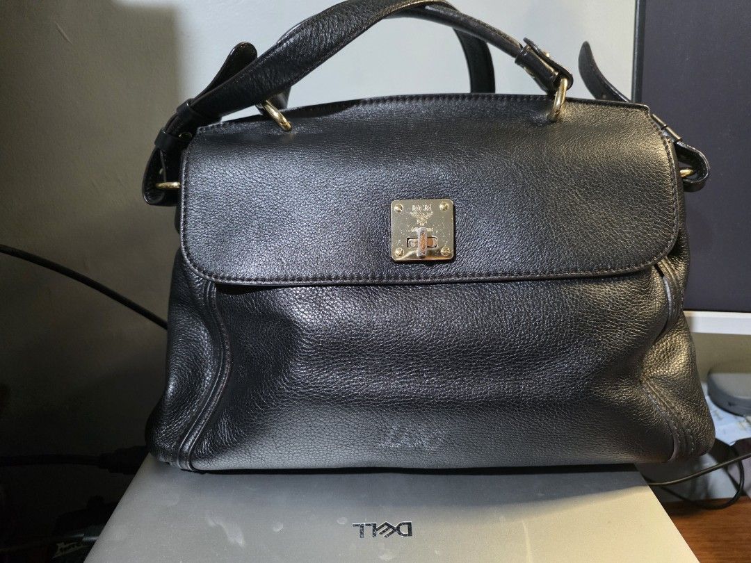 MCM Black Leather Top Handle Bag (Category: Luxury Bags & Wallets) located in Mandaluyong City. Submitted by artlin04 (Listing ID 1462307012, Image 1). Description: - Authentic MCM handbag in classic black leather. - Elegant gold-tone hardware, including the signature MCM logo clasp. - Spacious interior with MCM logo lining and a convenient zippered pocket. - Features sturdy top handles for comfortable carrying. - Secure flap closure to keep your