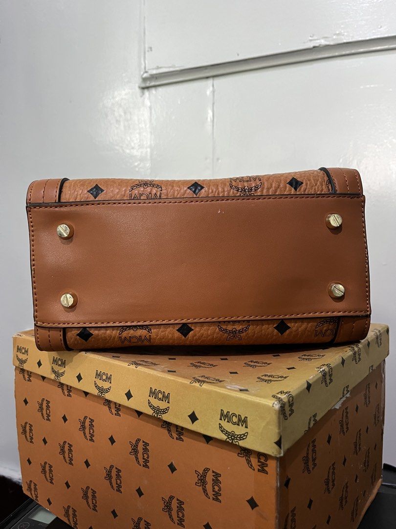 MCM Monogram Leather Top Handle Bag (Category: Luxury Bags & Wallets) located in Baguio. Submitted by azcollections_scar (Listing ID 1462336058, Image 3). Description: - Classic MCM monogram handbag - Tan leather with gold hardware - Top handle - Secure clasp closure - Interior zipped pocket - Comes with original MCM box - with dust bag & receipts - made in Korea - issue:missing lock seen on picture 6,800 HKD original price Accepting good offers 