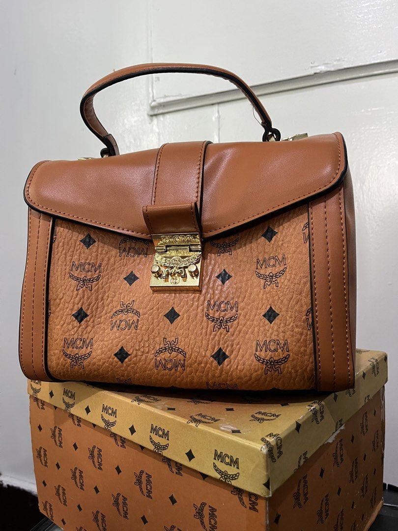 MCM Monogram Leather Top Handle Bag (Category: Luxury Bags & Wallets) located in Baguio. Submitted by azcollections_scar (Listing ID 1462336058, Image 1). Description: - Classic MCM monogram handbag - Tan leather with gold hardware - Top handle - Secure clasp closure - Interior zipped pocket - Comes with original MCM box - with dust bag & receipts - made in Korea - issue:missing lock seen on picture 6,800 HKD original price Accepting good offers 