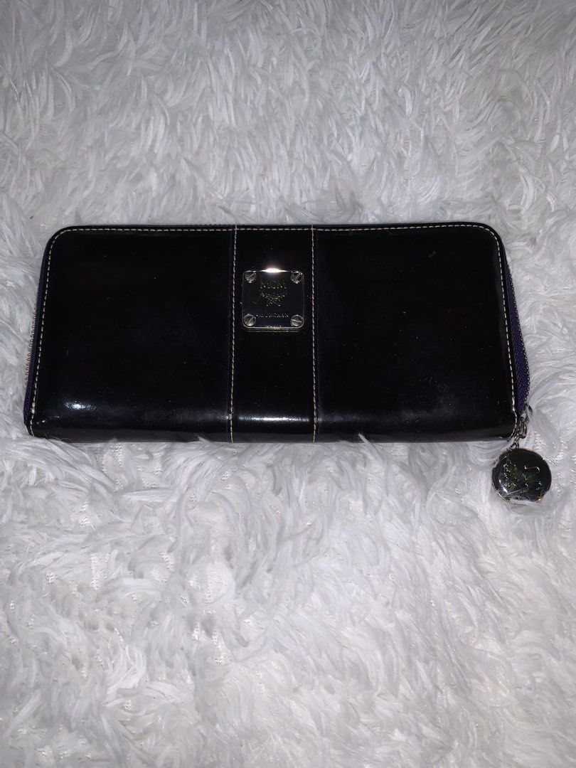 MCM wallet (Category: Wallets & Card holders) located in Manila. Submitted by bloobellyyy (Listing ID 1462265584, Image 1). Description: Style: Zip-around long wallet or organizer Material & Color: Smooth, dark black leather Design Details: Vertical central panel with white contrast stitching and a signature silver- or gold-toned metal MCM logo plaque on the front Closure: Full perimeter zipper to keep contents secure.
