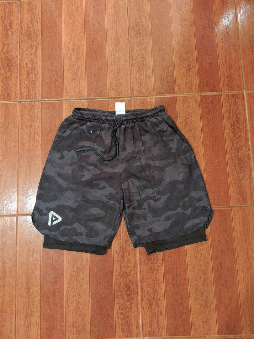 Men's Camo Athletic Shorts with Inner Liner (Category: Shorts) located in Matnog. Submitted by erasmoarnold.b9c007 (Listing ID 1462308553, Image 1). Description: - Dark grey camouflage shorts - Built-in black liner for support - Elastic waistband with adjustable drawstring - Versatile for workouts or casual wear - Features a logo on the left leg.