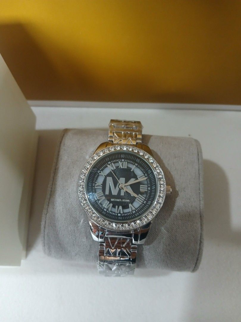 Michael Kors Watch with Crystal Bezel (Category: Women's Watches) located in Manila. Submitted by alegriacyr19 (Listing ID 1462322625, Image 2). Description: - Top Grade Watch - Authentic Michael Kors watch - Elegant silver-tone metal band - Classic black dial featuring Roman numerals and iconic MK logo - Sparkling crystal-embellished bezel - Comes with original box and dust bag - Perfect statement accessory to elevate any outfit.