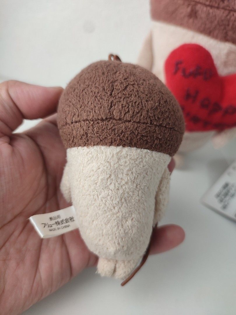 nameko mushroom plush strap mascot (Category: Plushies & Soft Toys) located in Manila. Submitted by epicmountain-f20453 (Listing ID 1462408214, Image 3). Description: - Adorable mushroom plush charm - Features a yellow cloth with Japanese writing - Includes a loop for easy hanging - Larger plush in background holds a red heart saying 'Fufu Happy Birthday' - Ideal for collectors or as a thoughtful gift.