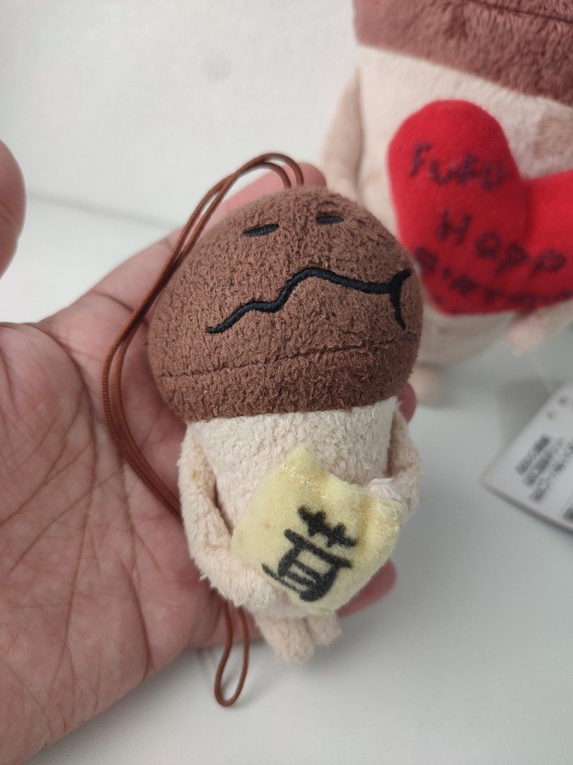 nameko mushroom plush strap mascot (Category: Plushies & Soft Toys) located in Manila. Submitted by epicmountain-f20453 (Listing ID 1462408214, Image 1). Description: - Adorable mushroom plush charm - Features a yellow cloth with Japanese writing - Includes a loop for easy hanging - Larger plush in background holds a red heart saying 'Fufu Happy Birthday' - Ideal for collectors or as a thoughtful gift.
