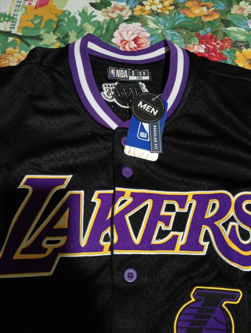 NBA Los Angeles Lakers Baseball Jersey (Category: Activewear) located in Caloocan City. Submitted by yazzielux (Listing ID 1462432026, Image 3). Description: - Black Los Angeles Lakers baseball jersey - Features iconic Lakers logo and name across the chest - Purple and white trim on collar and sleeves - Classic button-up front design - Made with breathable mesh fabric - Size S - Ideal for any dedicated Lakers fan!.