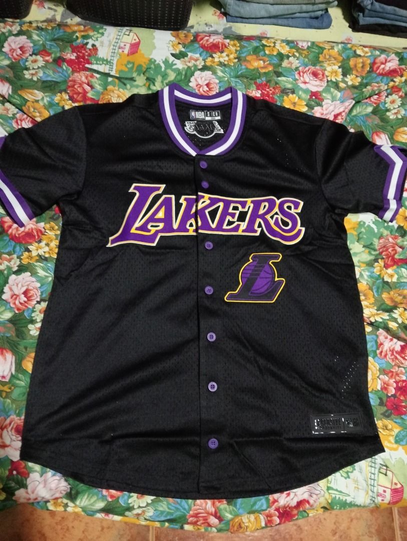 NBA Los Angeles Lakers Baseball Jersey (Category: Activewear) located in Caloocan City. Submitted by yazzielux (Listing ID 1462432026, Image 1). Description: - Black Los Angeles Lakers baseball jersey - Features iconic Lakers logo and name across the chest - Purple and white trim on collar and sleeves - Classic button-up front design - Made with breathable mesh fabric - Size S - Ideal for any dedicated Lakers fan!.