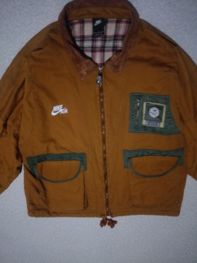 Nike Air Brown Jacket with Plaid Lining (Category: Coats, Jackets and Outerwear) located in Pili. Submitted by montealegr37922 (Listing ID 1462396228, Image 2). Description: - Brown Nike Air jacket - Cozy plaid lining inside - Two front pockets with stylish green trim - Bold Nike Air logo on the back - Classic corduroy collar detail - Adjustable drawstring hem - Ideal for everyday casual wear.