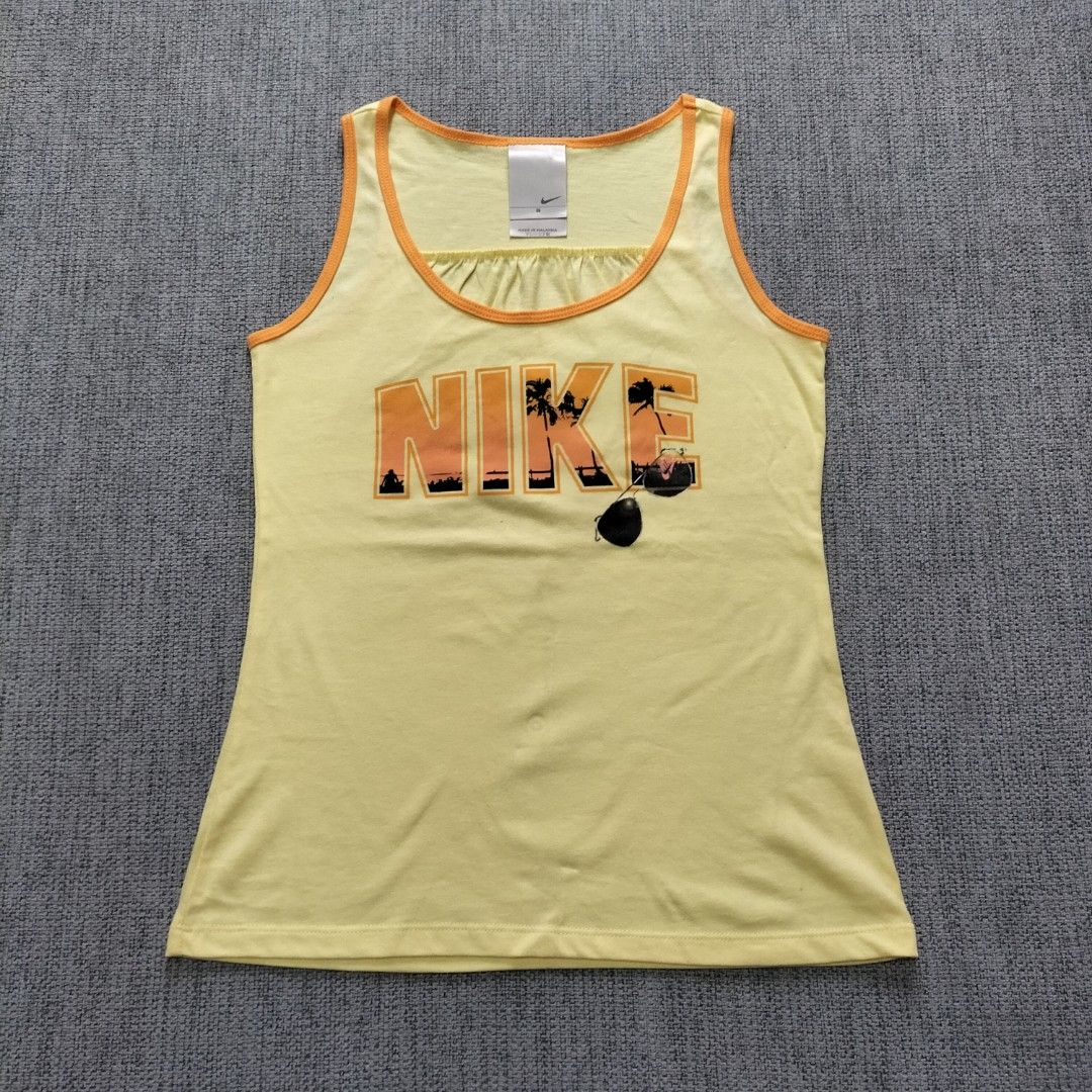 Nike Yellow Tank Top Size S (Category: Sleeveless) located in Taytay. Submitted by calmtree-6248 (Listing ID 1462364294, Image 1). Description: - Yellow Nike tank top with orange trim - Front graphic print: 'NIKE' text and tropical scene - Small Nike logo on the back - Material: 100% Cotton - Care: Machine washable cold - Size: S - Ideal for casual wear or workouts.