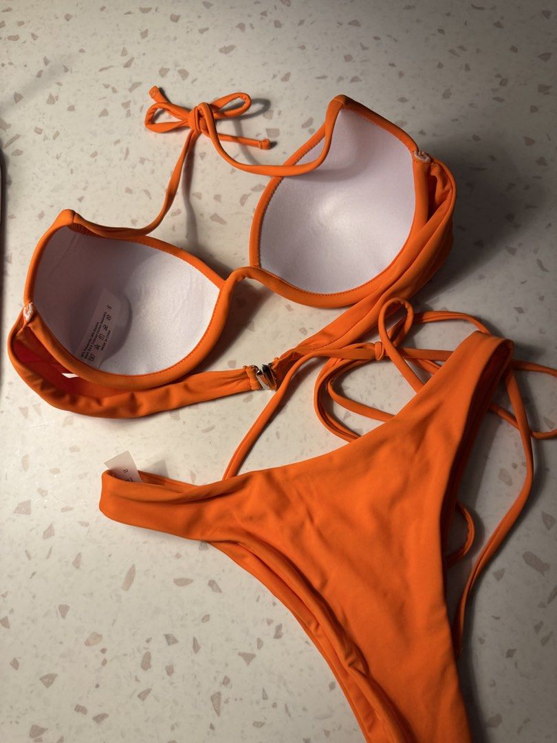 Orange String Bikini Set (Category: Bikinis & Swimsuits) located in Las Pinas. Submitted by patringcia_14 (Listing ID 1462324201, Image 2). Description: - Vibrant bright orange bikini set - Push-up top with adjustable straps - Tie-up bottoms for a customizable fit - Chic metal detail at the center of the top - Size S - Ideal for beach days and pool parties.