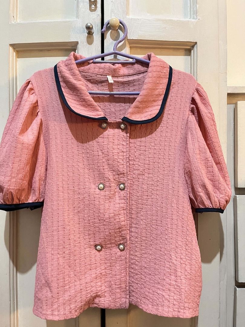 Pink Puff Sleeve Blouse (Category: Blouses) located in Quezon City. Submitted by bunniezen (Listing ID 1462356107, Image 3). Description: - Pink blouse with a unique textured fabric. - Puff sleeves with elegant navy trim. - Classic Peter Pan collar, also accented with navy trim. - Stylish double-breasted button front adorned with delicate pearl buttons. - Effortlessly pairs with skirts or trousers for a chic look. - Easy to style for various occa
