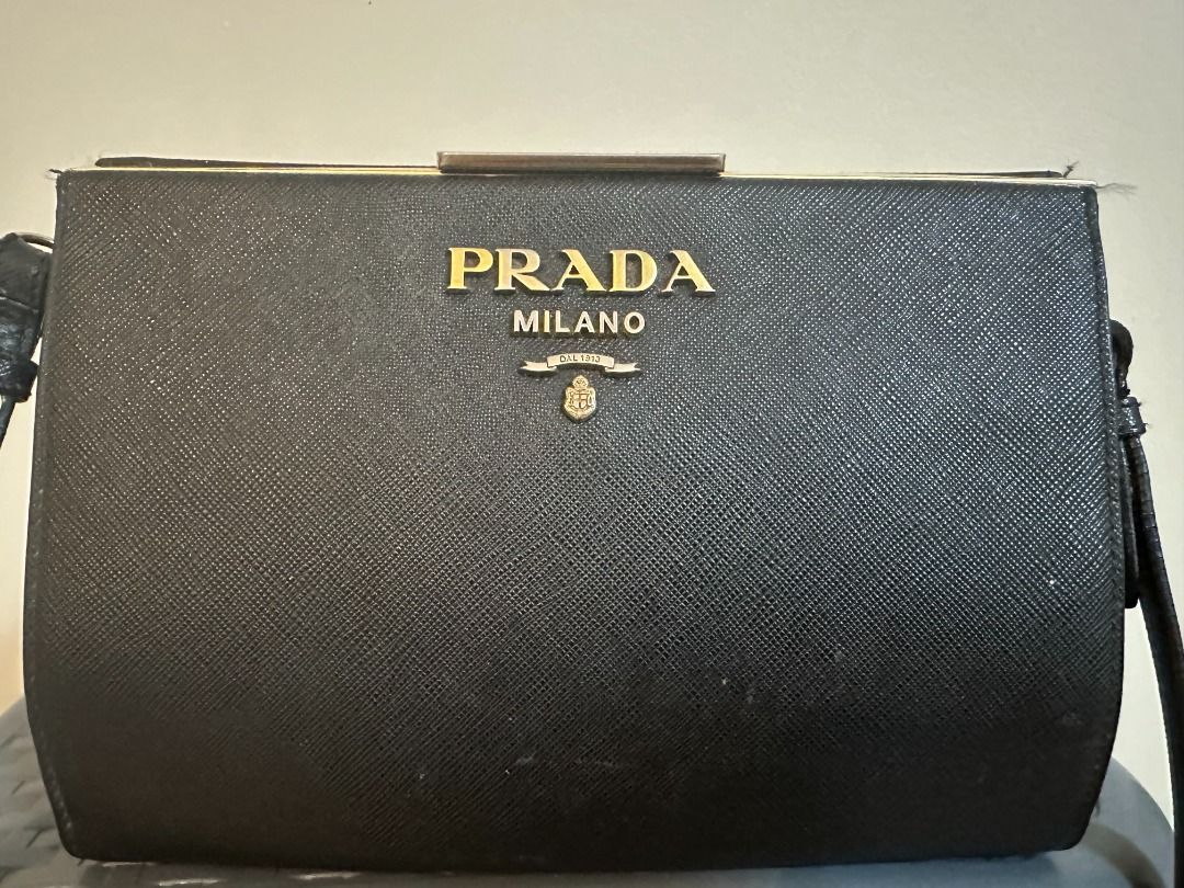 Pre-Owned Authentic Prada Light Frame Safiano Leather Bag (Category: Luxury Bags & Wallets) located in Pasay City. Submitted by sofiadeclutter_10 (Listing ID 1462337868, Image 1). Description: This is an pre-owned authentic PRADA Saffiano City Calfskin Light Frame Bag in Black. This chic bag is crafted from stylish saffiano cross-grain leather in black. The bag features an adjustable shoulder strap and gold hardware. The top opens to a black leat