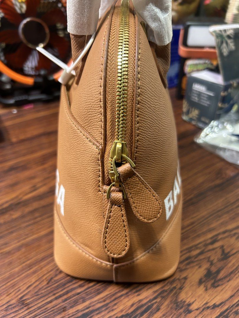 Replica Balenciaga Brown Leather Dome Handbag (Category: Luxury Bags & Wallets) located in Manila. Submitted by starbalesukandjapansurplus (Listing ID 1462437140, Image 2). Description: - Genuine brown leather dome handbag - Authentic Balenciaga logo - Secure gold zipper closure - Interior zippered pocket for essentials - Handles still have protective plastic wrap - Spotless interior condition - Ideal for everyday carry.