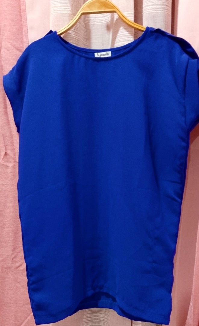 Royal blue tops (Category: Blouses) located in Cabanatuan. Submitted by miss.maia (Listing ID 1462423088, Image 3). Description: This royal blue short-sleeve top from the brand Sybaris features a clean, boat-neck collar design with extended shoulder/cap sleeves. It provides a simple, modern look perfect for both casual everyday wear and business-casual layering..