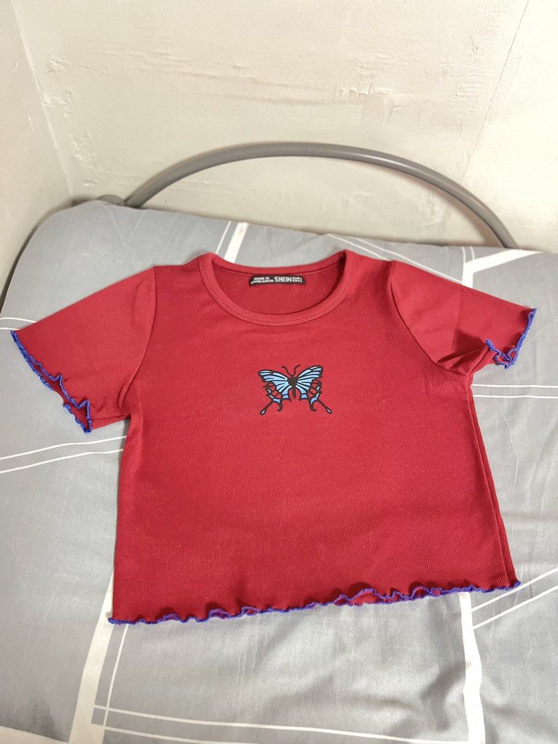 SHEIN Red Butterfly Lettuce Hem Crop Top (Category: Shirts) located in Manila. Submitted by thelvieee (Listing ID 1462312973, Image 1). Description: - Cute red crop top from SHEIN - Features a blue butterfly graphic on the front - Lettuce hem on sleeves and bottom with purple trim - Ribbed material for a comfortable fit - Ideal for a casual and fun everyday look.
