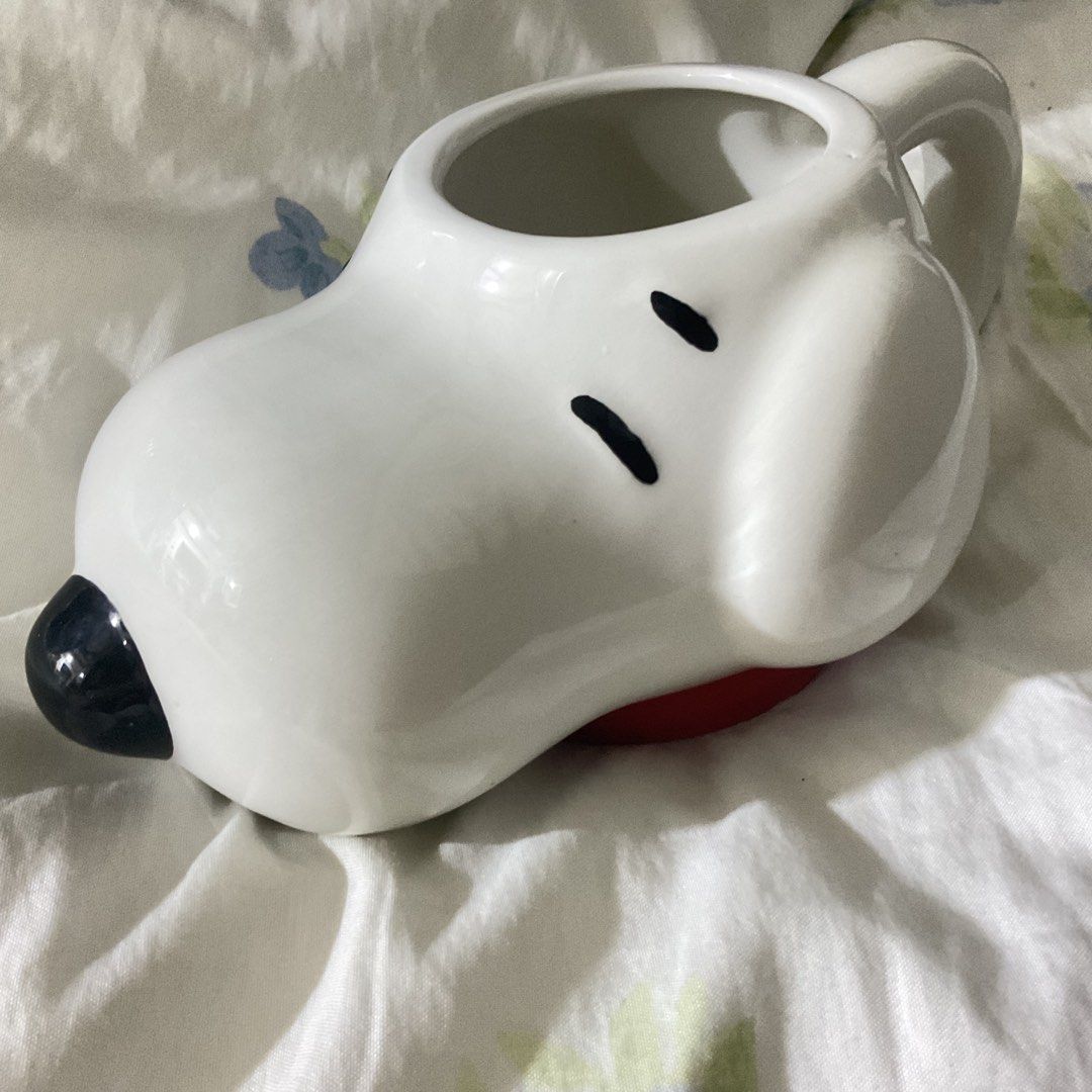 Snoopy Ceramic Mug (Category: Coffee & Tea Tableware) located in Naga. Submitted by asrid.32 (Listing ID 1462363087, Image 1). Description: - Adorable Snoopy-shaped mug - Classic white ceramic with black eyes and nose - Charming red detail at the base - Ideal for your morning coffee or evening tea - A must-have for any Snoopy enthusiast - Adds a fun touch to your kitchenware.