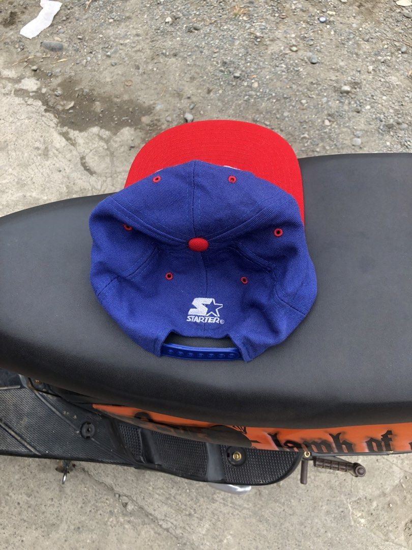 Starter New York Giants NFL Snapback Cap (Category: Caps & Hats) located in Montevista. Submitted by rdthriftshub (Listing ID 1462327173, Image 2). Description: - Classic blue and red New York Giants snapback cap - Iconic 'NY' logo embroidered on the front - Made by Starter, 100% wool - Green underside of the brim - Adjustable snapback closure for a comfortable fit - Perfect for any Giants fan.