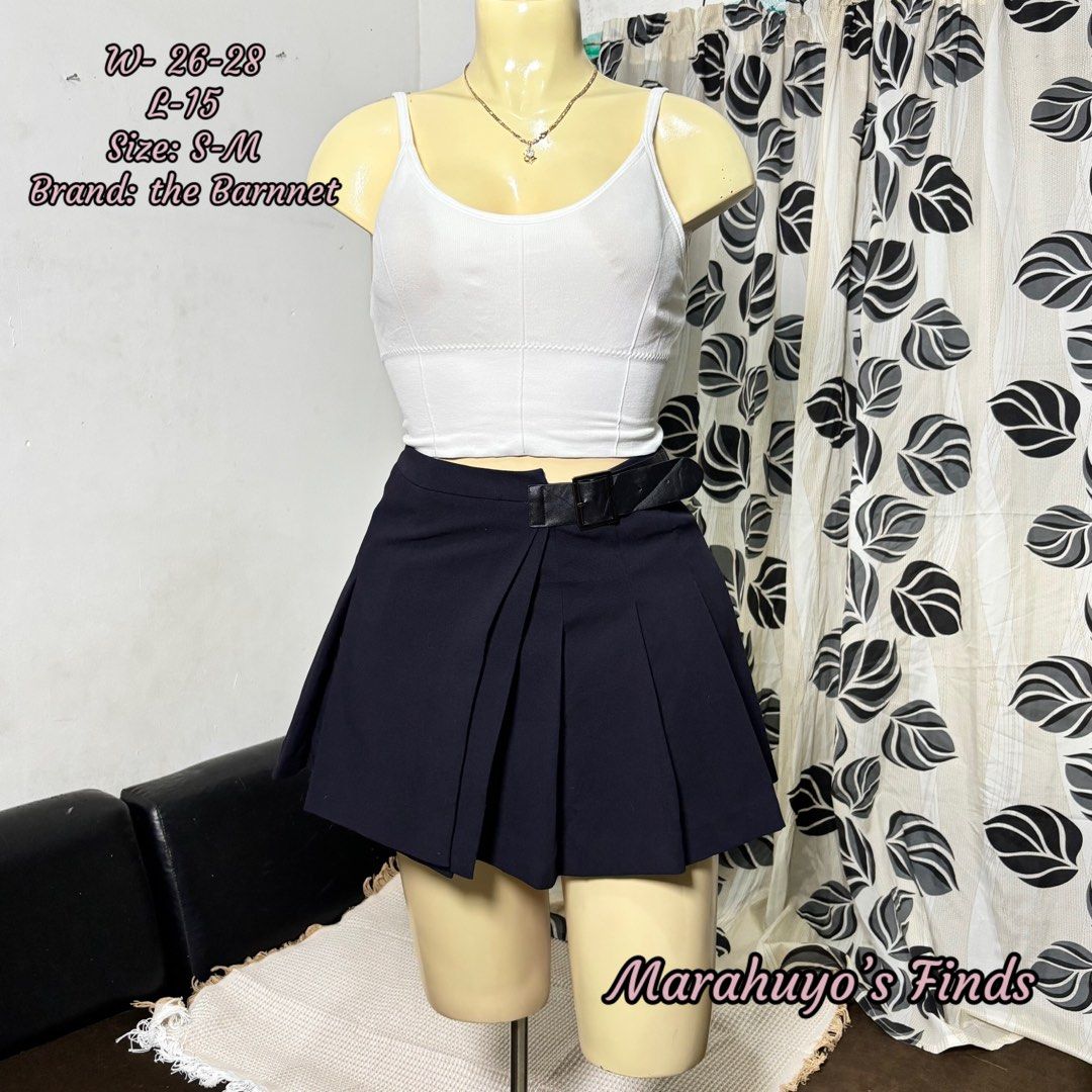 The Barnnet Navy Pleated Buckle Strap Mini Skirt (Category: Skirts) located in Mabalacat. Submitted by marahuyos.finds (Listing ID 1462410402, Image 1). Description: - Navy pleated mini skirt - Brand: The Barnet - Size: Estimated S-M - Waist: 26-28 inches - Length: 15 inches - Features a stylish buckle strap detail at the waist - Versatile for preppy or casual looks - Pairs well with crop tops or blouses.