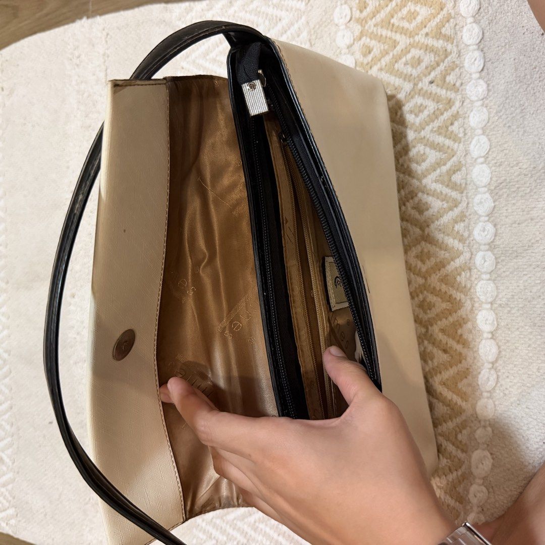 TIMES Cream and Black Shoulder Bag (Category: Shoulder Bags) located in Batangas. Submitted by prelove.kk (Listing ID 1462402730, Image 2). Description: - Cream and black shoulder bag by TIMES - Magnetic snap closure - Interior: 1 zippered pocket, 1 slip pocket - Tan colored lining - Black strap with silver buckle detail - Minor scuffs on the black bottom part - Interior is clean.