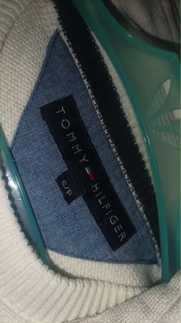 Tommy Hilfiger Sweater (Category: Coats, Jackets and Outerwear) located in Manila. Submitted by jenii_collective (Listing ID 1462406374, Image 3). Description: - Classic white V-neck sweater - Brand: Tommy Hilfiger - Material: Knitted - Features: Ribbed cuffs and hem, small embroidered logo on chest - Style: Versatile, great for layering or wearing alone.