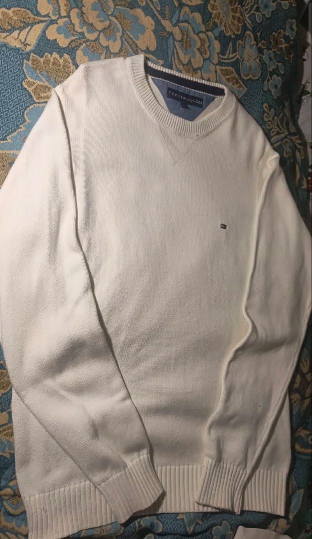 Tommy Hilfiger Sweater (Category: Coats, Jackets and Outerwear) located in Manila. Submitted by jenii_collective (Listing ID 1462406374, Image 1). Description: - Classic white V-neck sweater - Brand: Tommy Hilfiger - Material: Knitted - Features: Ribbed cuffs and hem, small embroidered logo on chest - Style: Versatile, great for layering or wearing alone.