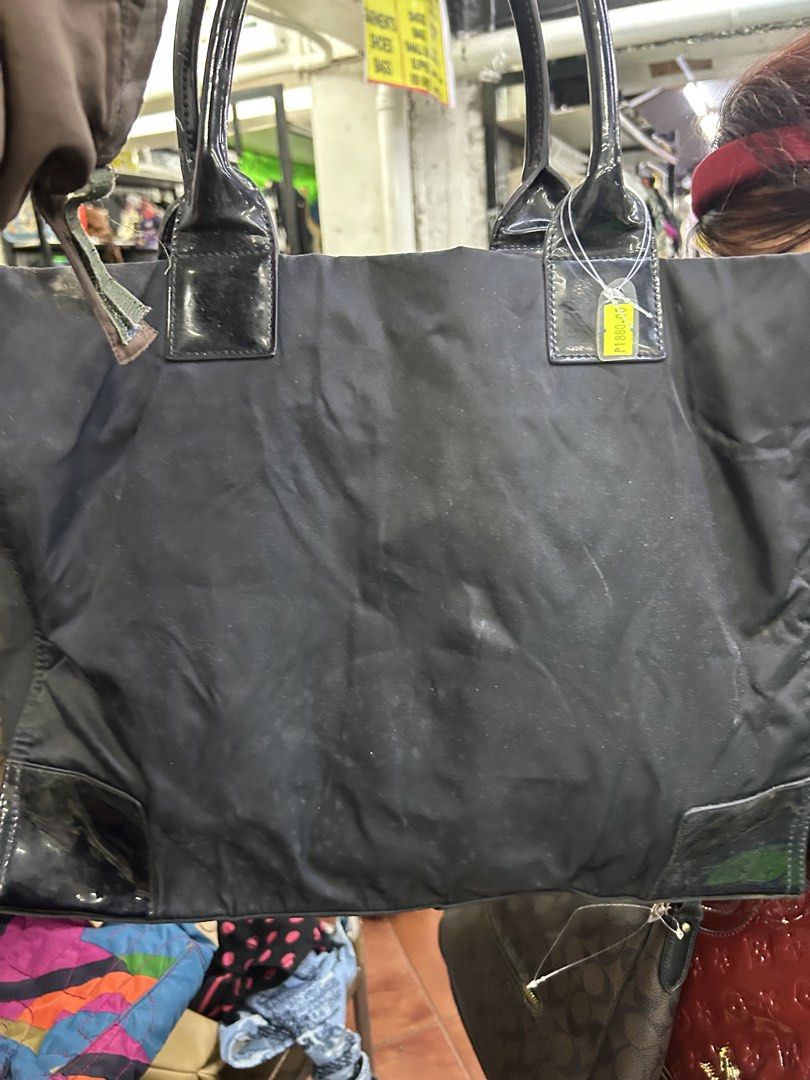 Tory Burch Black Nylon Tote Bag (Category: Tote Bags) located in Balanga. Submitted by coolwhale-76ba (Listing ID 1462406609, Image 3). Description: - Classic black Tory Burch tote bag - Made with durable nylon and patent leather accents - Spacious interior with a zippered pocket - Iconic Tory Burch logo on the front - Shiny patent leather handles - Great for everyday use or travel.