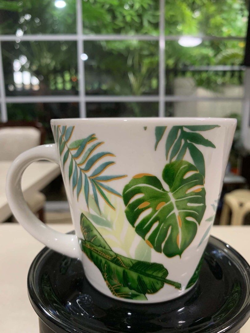 Tropical Leaf Print Ceramic Mug (Category: Coffee & Tea Tableware) located in Quezon City. Submitted by meggoquingco (Listing ID 1462376182, Image 2). Description: - White ceramic mug - Vibrant tropical leaf print (monstera & palm) - Shades of green and teal leaves - Gold accent details - Perfect for coffee or tea.