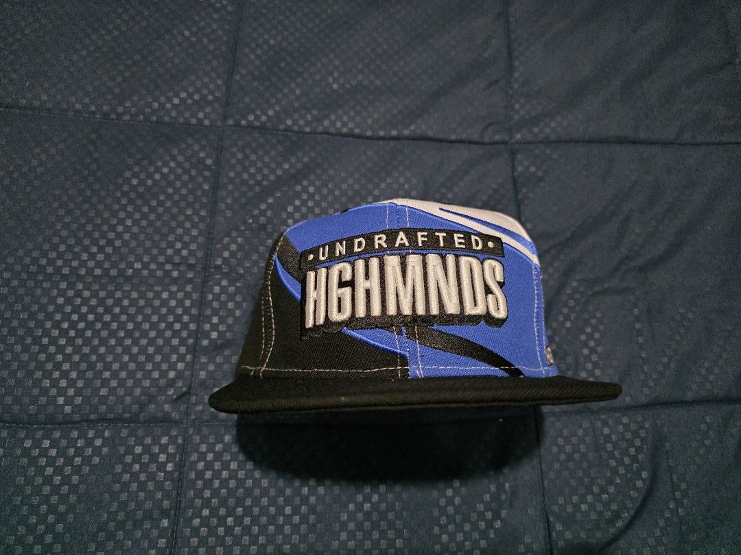 Undrafted Highmnds Snapback Cap (Category: Caps & Hats) located in Santa Rosa. Submitted by wel3993 (Listing ID 1462315797, Image 2). Description: highminds x undrafted Brandnew 1500 MOD. LBC MOP. BDO, GCASH LOC. NUEVA ECIJA - Stylish snapback cap with 'Undrafted Highmnds' text. - Features a cool white, blue, and black colorway. - Designed with a flat brim for a classic look. - Adjustable strap at the back for a comfortable, customized fit. - Ide