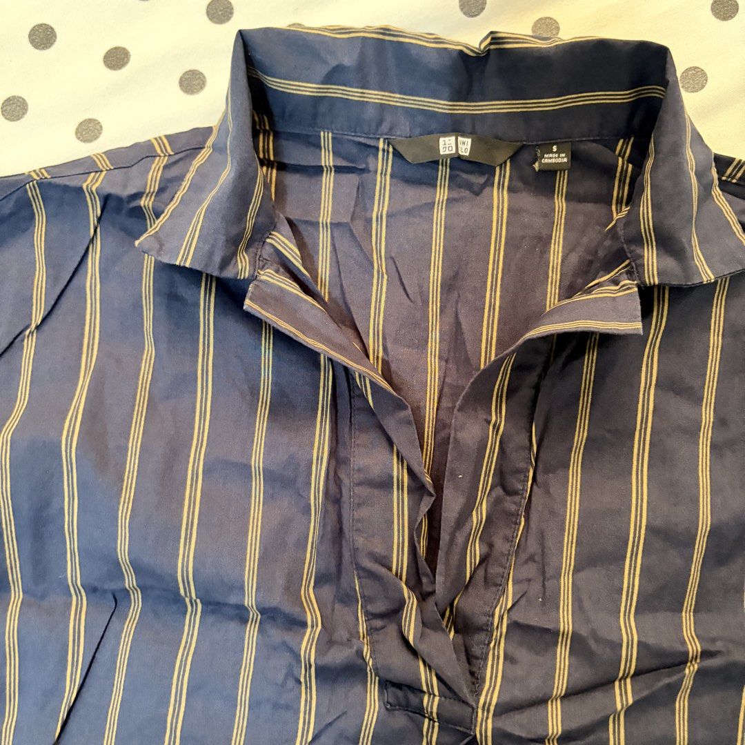 Uniqlo Navy Striped Collared Shirt (Category: Shirts) located in Pasay City. Submitted by notellyyyy (Listing ID 1462279311, Image 2). Description: - Navy blue shirt with subtle thin gold stripes - Short sleeves and a classic collared neckline - V-neck opening with a convenient button closure - Relaxed fit for ultimate comfort - Ideal for everyday casual wear.