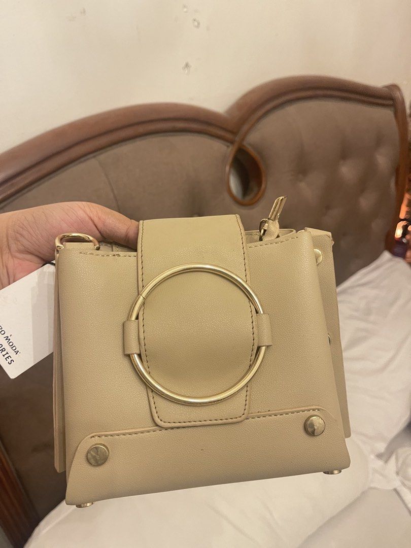 Vero Moda Beige Ring Handle Handbag UNUSED (Category: Shoulder Bags) located in Marilao. Submitted by wardrovearchives (Listing ID 1462273727, Image 1). Description: - Brand: Vero Moda - Color: Beige - Handle: Gold ring handle - Closure: Secure zip closure - Details: Small gold studs on the bottom - Interior: 1 zip pocket, 1 slip pocket - Condition: Brand new with original tag attached.
