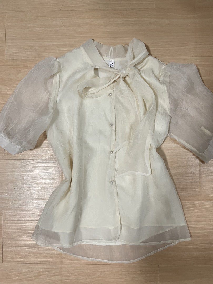 White Puff Sleeve Bow Koren Formal See Through Blouse (Category: Blouses) located in San Juan, La Union. Submitted by nicaaas (Listing ID 1462370548, Image 1). Description: - no issues laid flat measurements: waist: 18 inches length: 24” arms: 6” - Cream white blouse - Sheer puff sleeves - Tie-bow detail at the neck - Pearl button front closure - Subtle textured fabric pattern - Versatile for dressy casual looks, pairs well with skirts or high-wa
