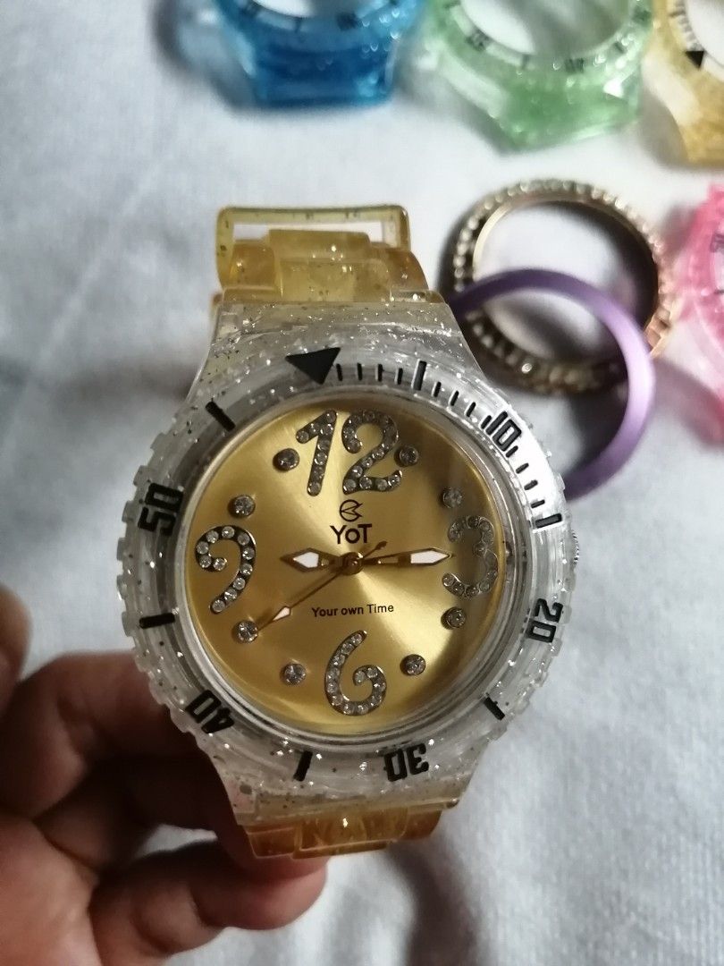 YOT Watch with Interchangeable Bezel and Straps (Category: Women's Watches) located in Quezon City. Submitted by globaltravelboutique (Listing ID 1462310285, Image 1). Description: - YOT watch with a gold dial - Includes multiple colorful bezels for easy outfit matching - Clear watch band and bezel with glitter accents - Water resistant up to 10 ATM - Perfect for creating a personalized style.