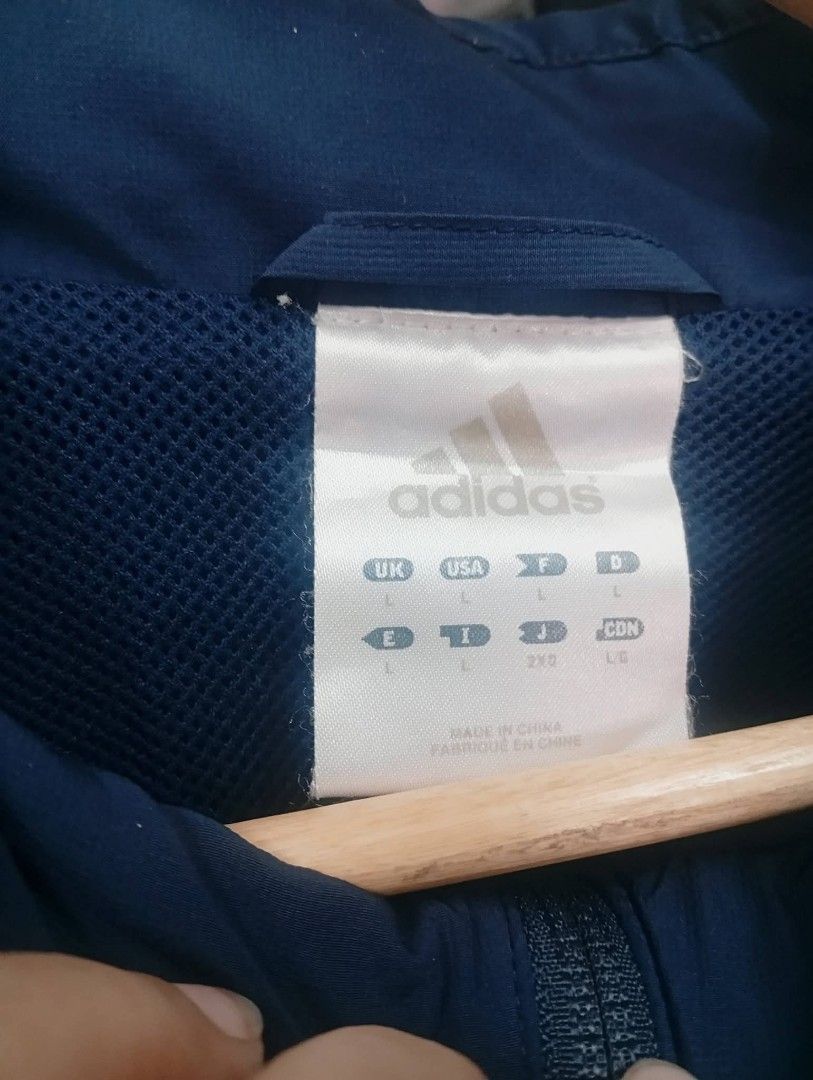 Adidas Navy Blue Track Jacket (Category: Coats, Jackets and Outerwear) located in Manila. Submitted by annemanzano120906 (Listing ID 1462553096, Image 2). Description: - Navy blue Adidas track jacket - Size L - Light blue and red accents on the front - Three white stripes on the sleeves - Features pockets - Drawstring at the hem.