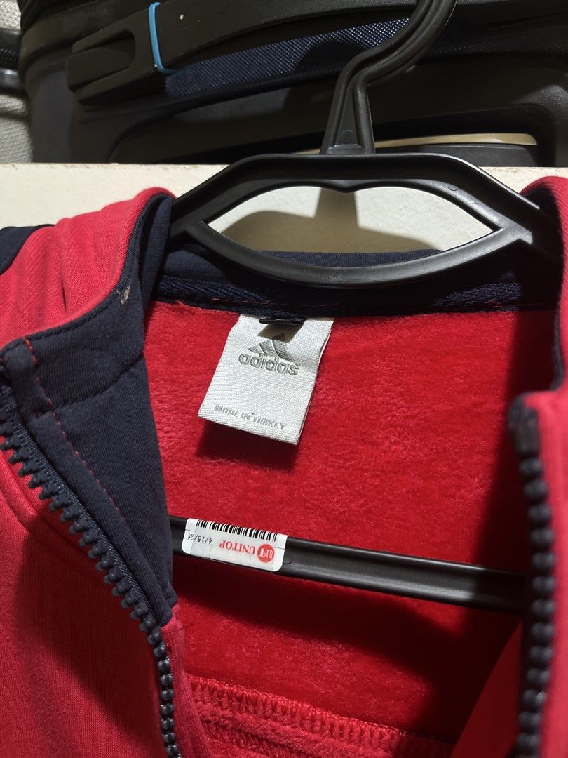 Adidas Red Zip-Up Hoodie Jacket (Category: Coats, Jackets and Outerwear) located in Manila. Submitted by jezrathrift (Listing ID 1462673113, Image 2). Description: - Red Adidas zip-up hoodie jacket - Classic navy blue three stripes on sleeves - Features a hood - Two front pockets - Made in Turkey - Ideal for casual wear or sports.