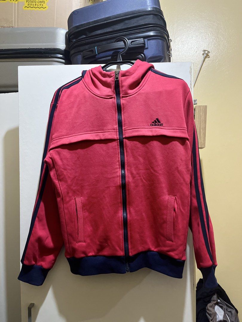 Adidas Red Zip-Up Hoodie Jacket (Category: Coats, Jackets and Outerwear) located in Manila. Submitted by jezrathrift (Listing ID 1462673113, Image 1). Description: - Red Adidas zip-up hoodie jacket - Classic navy blue three stripes on sleeves - Features a hood - Two front pockets - Made in Turkey - Ideal for casual wear or sports.