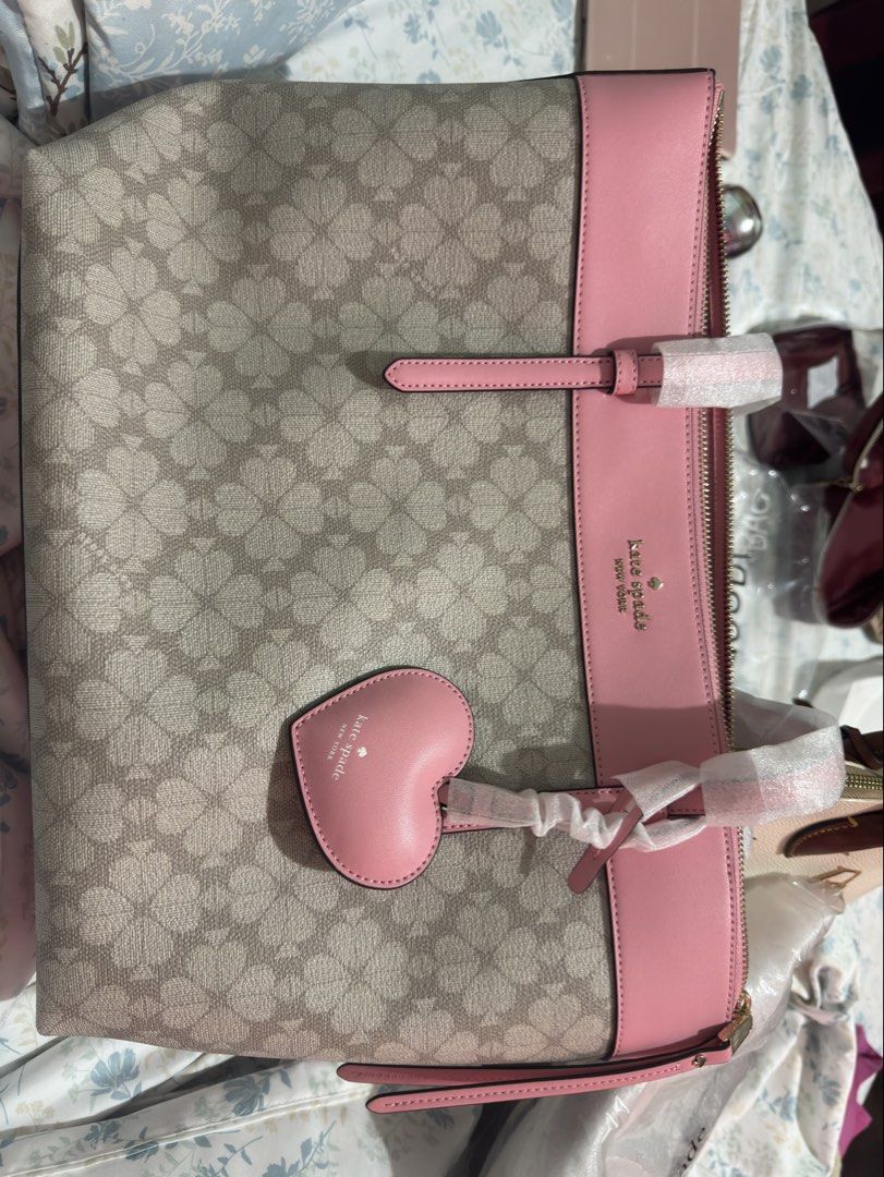 Authentic Kate Spade Tote Bag with Heart Charm (Category: Tote Bags) located in Cainta. Submitted by trufflecake (Listing ID 1462537975, Image 1). Description: - Authentic BRAND NEW Kate Spade tote bag - Features signature spade flower pattern - Adorable pink heart charm included - Stylish pink trim and handles - Comes with a detachable shoulder strap - Brand new with original tags attached.