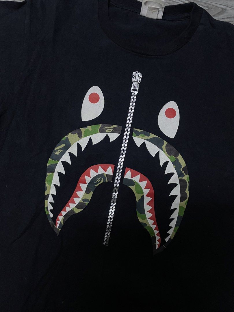 BAPE Shark Tee (Category: Tshirts & Polo Shirts ) located in Manila. Submitted by yourfavoriteplug (Listing ID 1462508180, Image 2). Description: - Authentic Black BAPE T-Shirt - Features the iconic camouflage shark mouth graphic - Zipper detail on the design - Size: Medium (M) - Essential piece for any streetwear enthusiast.
