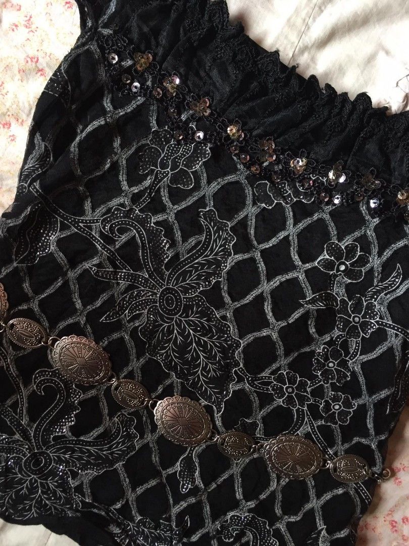 Black Off-Shoulder Top with Sequins and Embellishments (Category: Blouses) located in Aloran. Submitted by thriftfinds.co (Listing ID 1462533400, Image 2). Description: - Black off-shoulder top - Short sleeves with ruffled edges - Neckline adorned with lace trim and sequins - Unique patterned fabric with diamond net overlay - Comes with a silver-tone decorative belt - Fun and eye-catching piece.