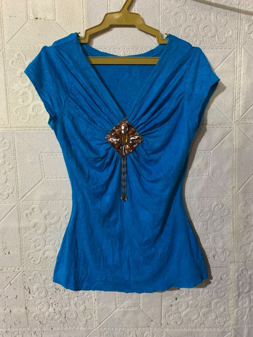 Blue V-Neck Top with Embellished Front (Category: Blouses) located in Caloocan City. Submitted by emmalizz (Listing ID 1462492587, Image 1). Description: - Bright blue short-sleeved top - V-neckline with gathered fabric detail - Decorative embellishment with beads and stones - Textured fabric for a unique look - Versatile for casual outings or dressing up.