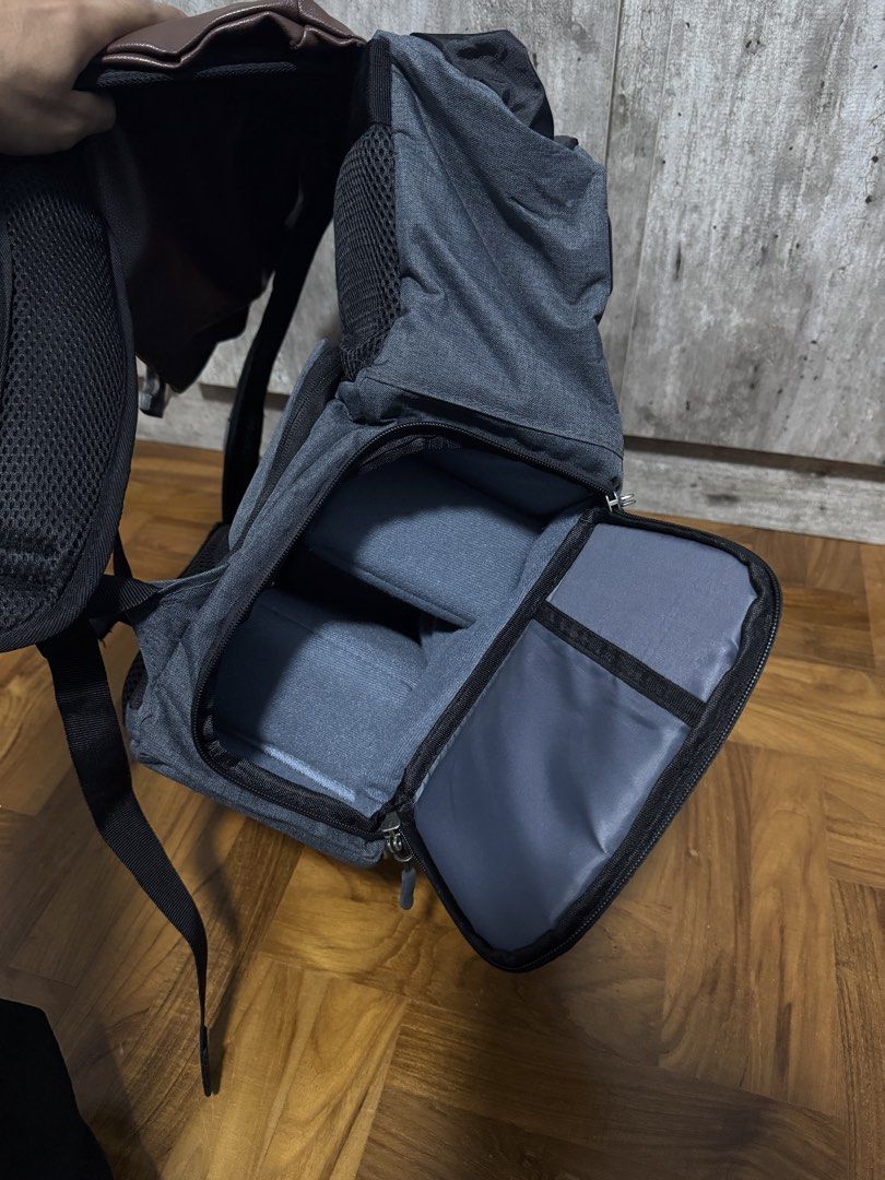Camera Backpack!! (Category: Backpacks) located in Singapore. Submitted by aniqkelodeon (Listing ID 1462551967, Image 4). Description: - Dark grey fabric body with brown faux leather flap - Main compartment secured by drawstring closure - Zippered pocket on the flap for extra security - Padded shoulder straps for comfortable carrying - Convenient side mesh pockets - Internal dividers, suitable for organizing camera equipment.