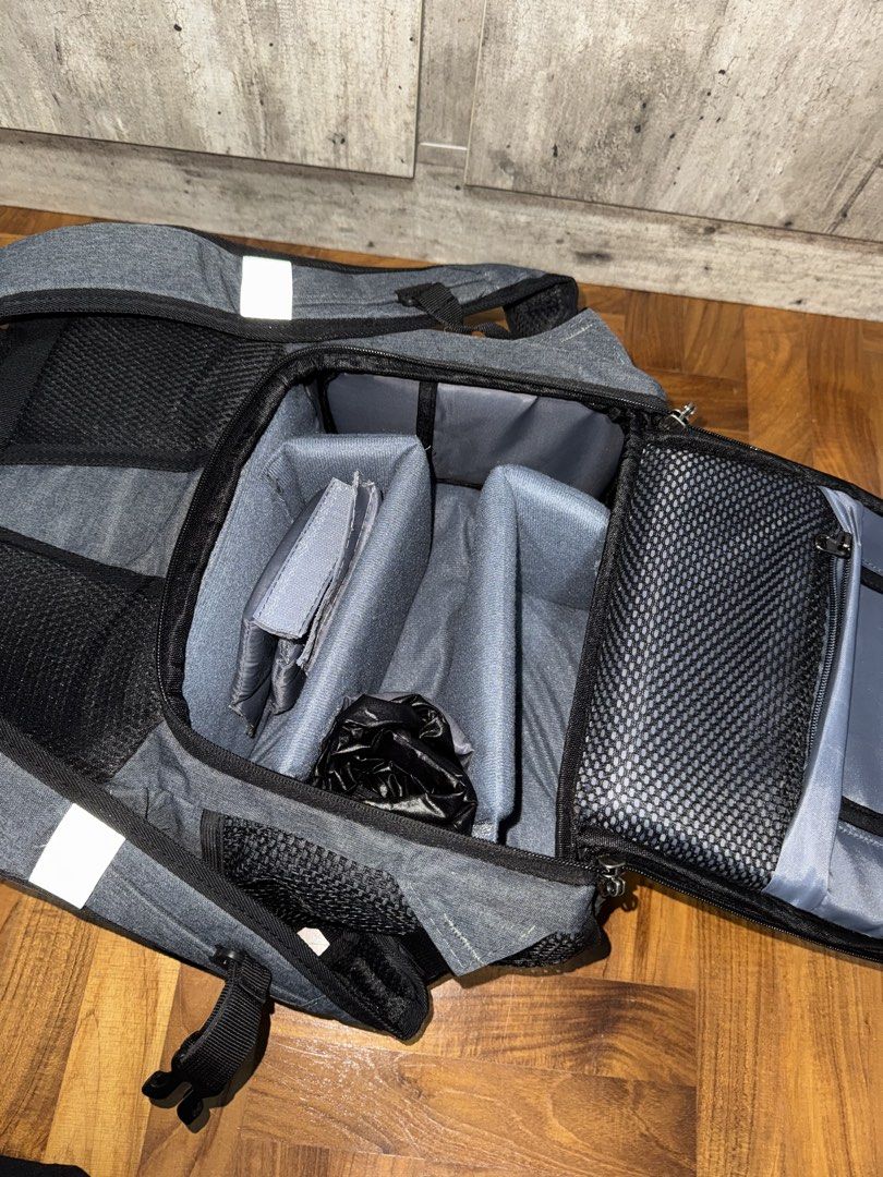 Camera Backpack!! (Category: Backpacks) located in Singapore. Submitted by aniqkelodeon (Listing ID 1462551967, Image 6). Description: - Dark grey fabric body with brown faux leather flap - Main compartment secured by drawstring closure - Zippered pocket on the flap for extra security - Padded shoulder straps for comfortable carrying - Convenient side mesh pockets - Internal dividers, suitable for organizing camera equipment.