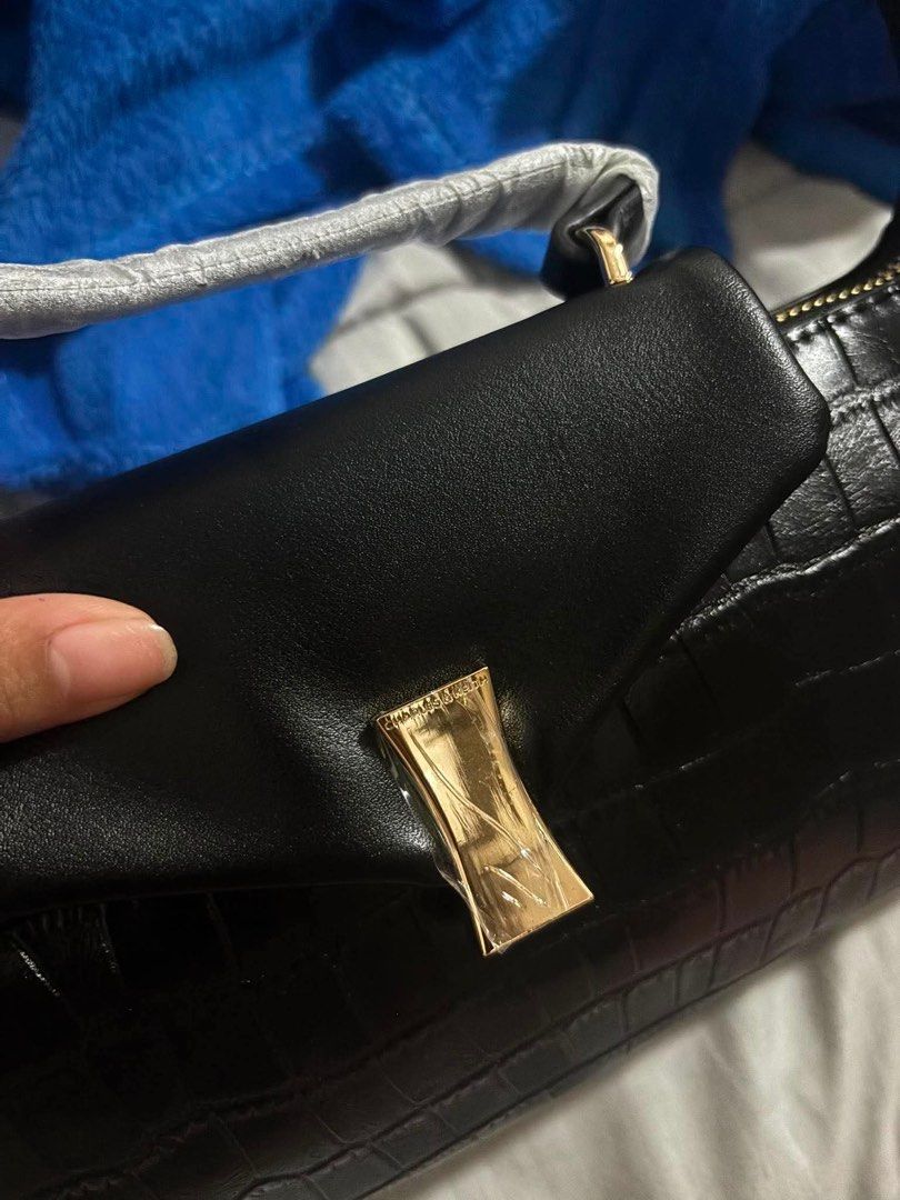 Charles & Keith Black Croc Embossed Top Handle Bag (Category: Luxury Bags & Wallets) located in Manila. Submitted by mcsantiago50683 (Listing ID 1462663091, Image 2). Description: - Brand: Charles & Keith - Color: Black - Texture: Croc embossed - Hardware: Gold details - Handles: Top handle - Strap: Detachable strap included - Closure: Zipper - Interior: Zip pocket - Inclusions: Dust bag and paper bag - Occasion: Versatile, suitable for any event