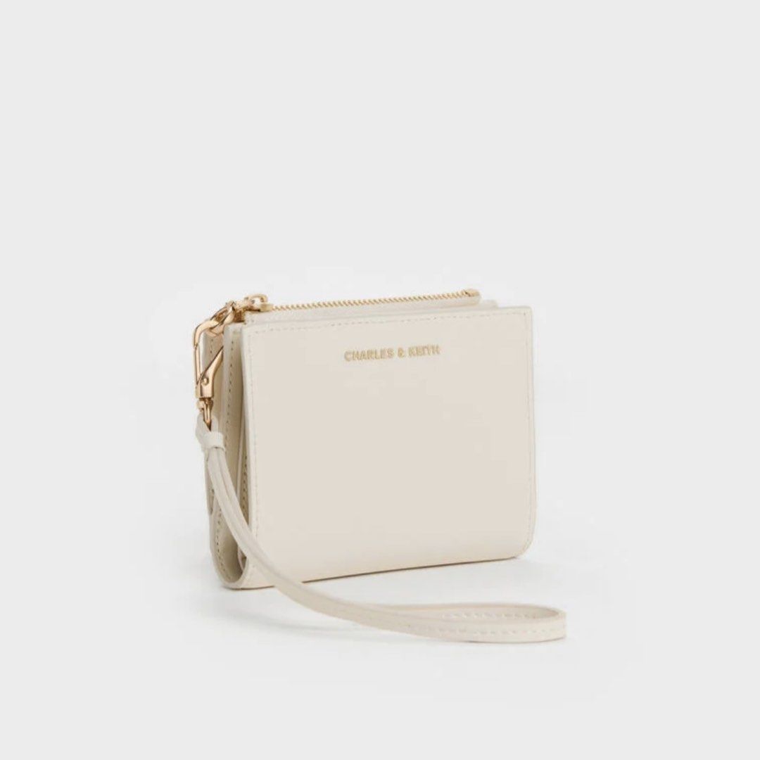 Charles & Keith Hanya Wallet (Cream) (Category: Wallets & Card holders) located in Manila. Submitted by 95ee70b1a701e3b2d80b53b0e4e92c (Listing ID 1462609404, Image 2). Description: Cream Charles & Keith wallet with zip-around closure, wrist strap, card slots, and coin pouch. Gold hardware. Compact and practical. Pass sa lowball .