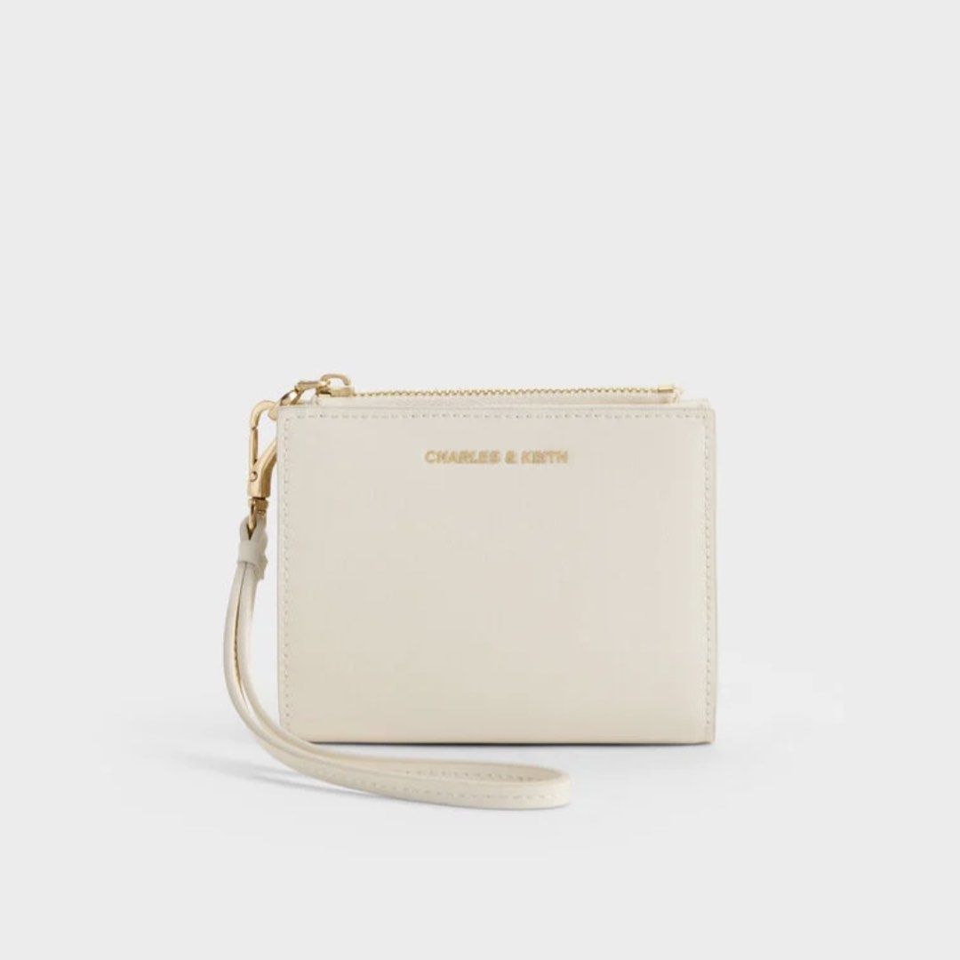 Charles & Keith Hanya Wallet (Cream) (Category: Wallets & Card holders) located in Manila. Submitted by 95ee70b1a701e3b2d80b53b0e4e92c (Listing ID 1462609404, Image 1). Description: Cream Charles & Keith wallet with zip-around closure, wrist strap, card slots, and coin pouch. Gold hardware. Compact and practical. Pass sa lowball .