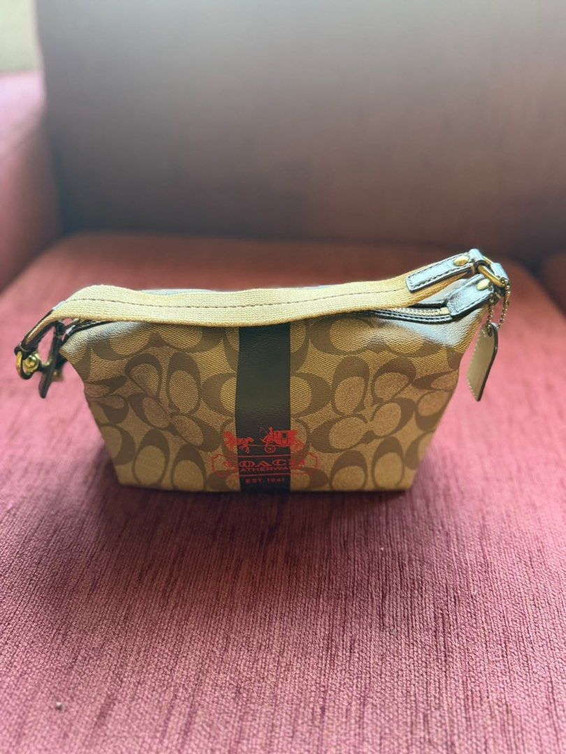 Coach Monogram Cosmetic Bag (Category: Shoulder Bags) located in Taguig. Submitted by sellall37207 (Listing ID 1462478659, Image 1). Description: - Authentic Coach monogram cosmetic bag - Color: Tan with brown 'C' pattern - Signature dark stripe with Coach logo detail - Secure zipper closure - Convenient small attached strap - Ideal for makeup, toiletries, or small personal items.